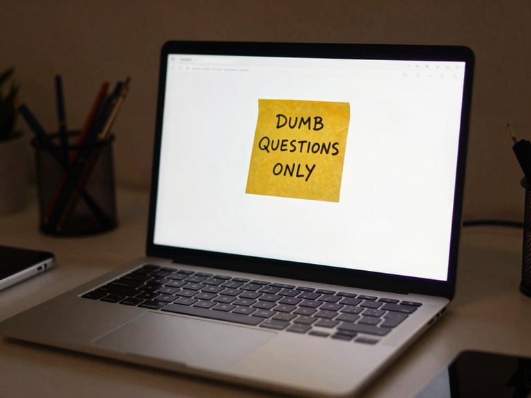 Cozy lo-fi photography of a messy desk with a glowing laptop screen displaying a yellow sticky note with 'DUMB QUESTIONS ONLY' written on it, warm monitor glow, shallow depth of field, 35mm