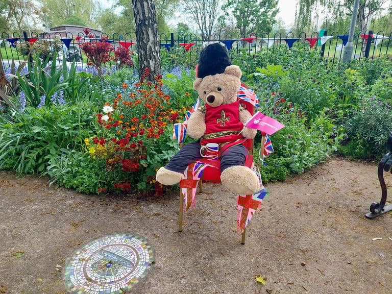 a teddy bear sitting on a chair in a garden