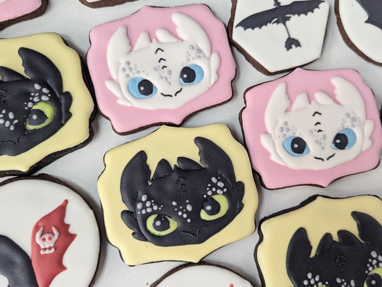 Cookies with yellow or pink icing, designed with How to Train Your Dragon characters