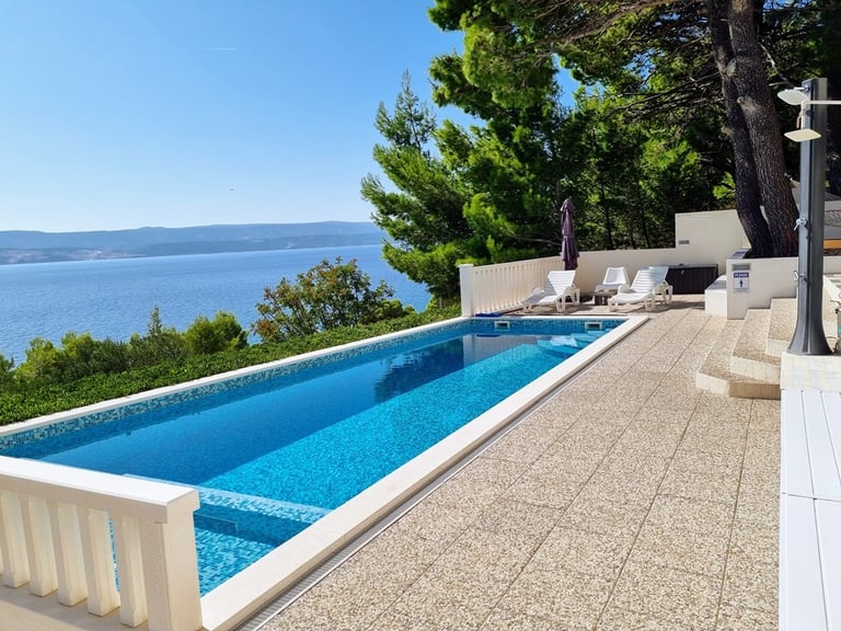 The photo shows a pool with a view of the western sun terrace and the sea.