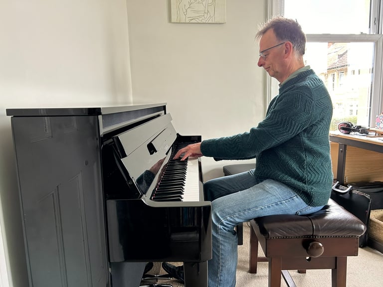 Photo of Steven playing an upright piano