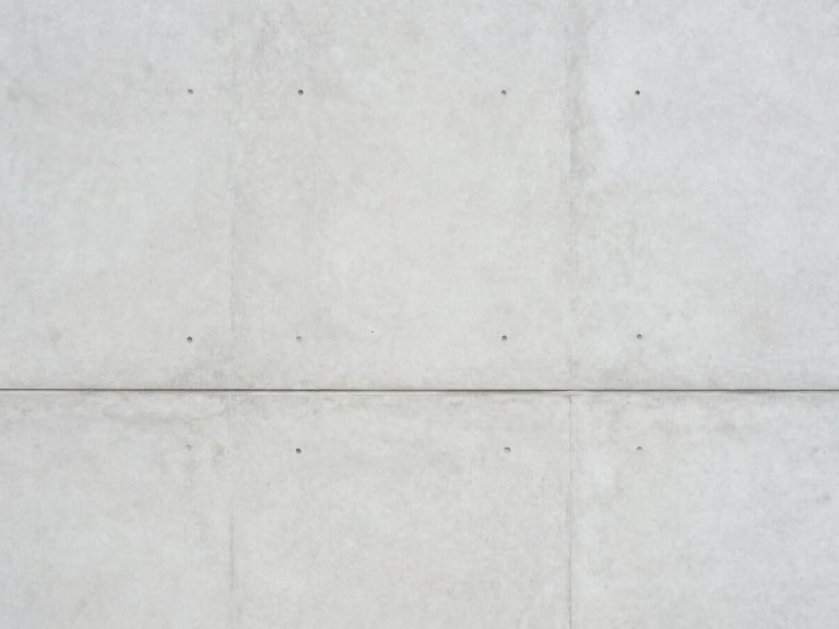 Minimalist architectural photography of a clean concrete facade with soft diffused daylight, muted light gray and slate tones, clean composition, 35mm