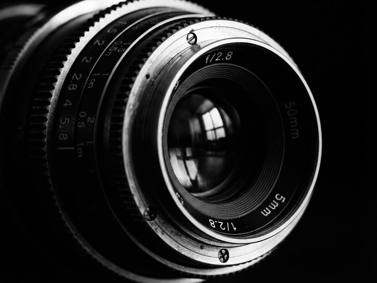 Extreme close-up of a high-end cinematic camera lens, sharp reflections, stark black and white, high-contrast chiaroscuro lighting, deep shadows