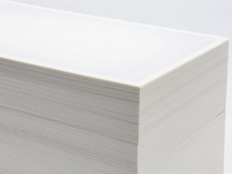 Neatly stacked bulk packaging of specialty paper with a subtle, customizable label area, bright clinical studio light