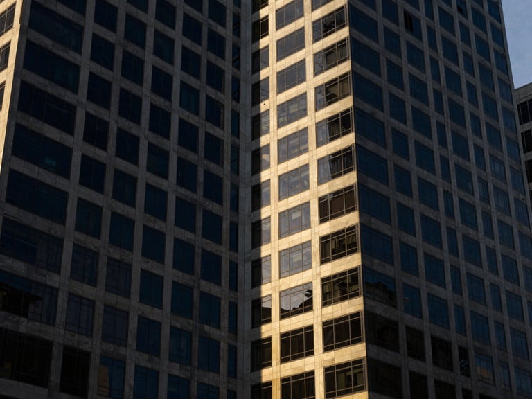 High-contrast architectural angle of modern office towers in Abuja's Central Business District, sharp directional window light, deep navy shadows, 35mm lens.