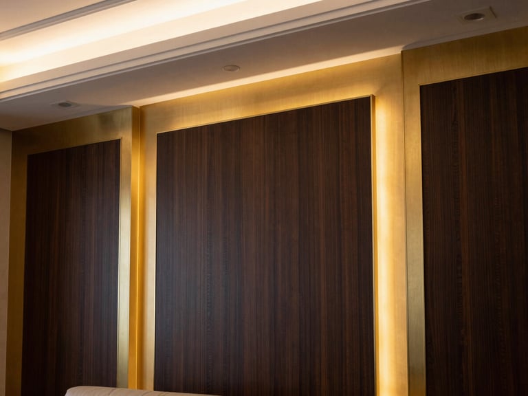 A close-up of a luxury Riyadh living room wall featuring brushed champagne gold trim and dark wood paneling, warm architectural LED lighting, 35mm lens