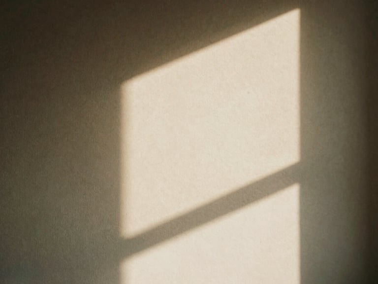 Abstract light pattern on a textured wall, created by soft, indirect window light, warm shadows, and muted earth tones, shallow depth of field.