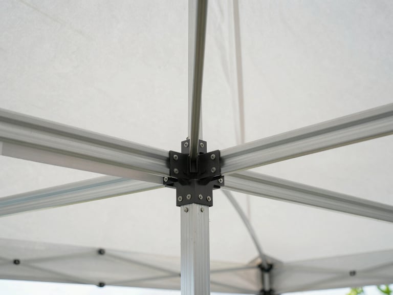 Symmetrical close-up of heavy-duty aluminum tent framing and clean white canvas canopy, highlighting structural integrity, crisp morning daylight, architectural precision.