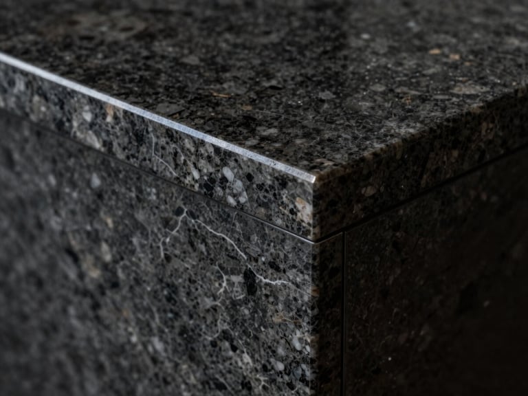 Extreme close-up of a flawless mitered joint (meia-esquadria) on a dark quartzite gourmet countertop, sharp directional lighting highlighting the seamless edge