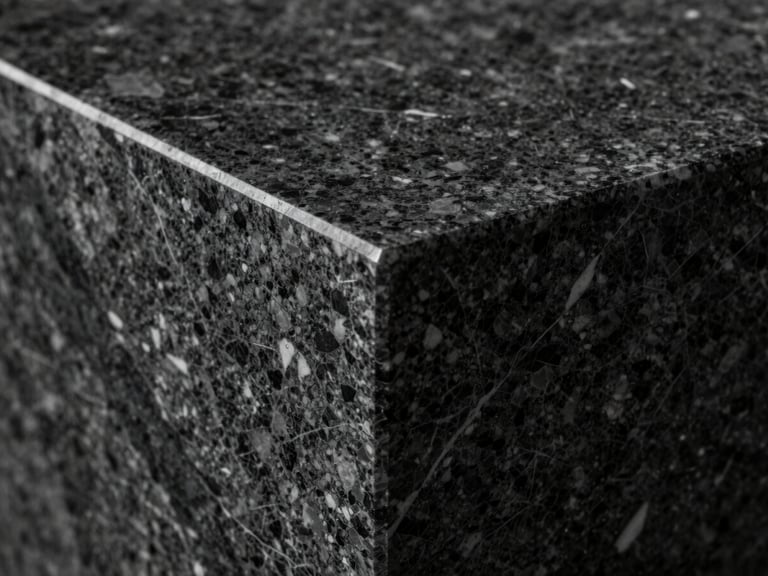 Macro close-up of a flawless mitered joint of a dark quartzite countertop, showcasing sharp 45-degree angles, continuous vein matching, and high-contrast directional lighting.