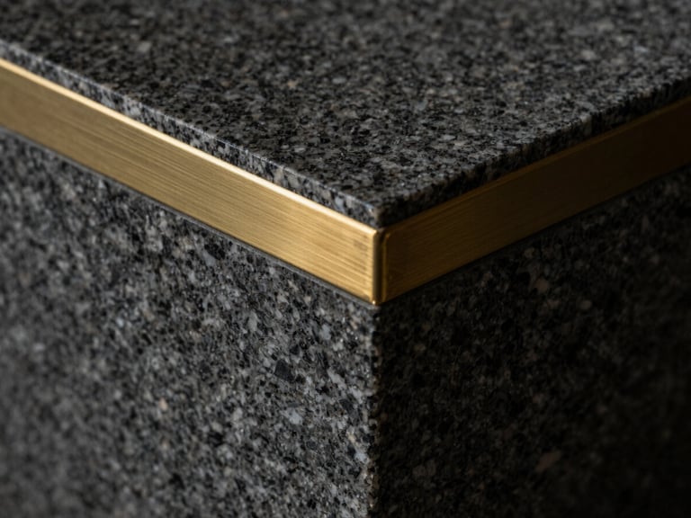 Extreme close-up of a heavy dark granite block with a single brushed brass inlay line, dramatic side lighting, deep shadows