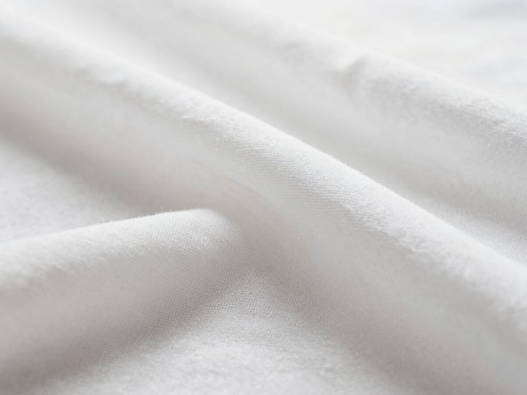 Close-up macro shot of crisp white linen fabric texture with clean folds under bright, natural diffused morning light, shallow depth of field, 35mm