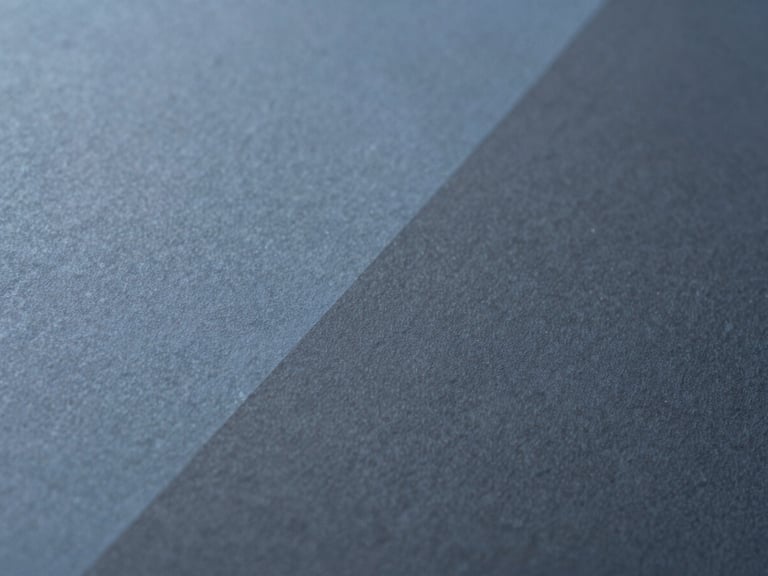 Extreme close-up of fine textured paper with abstract geometric shadows, minimalist editorial photography, soft diffused daylight, muted stellar blue and charcoal tones, 35mm