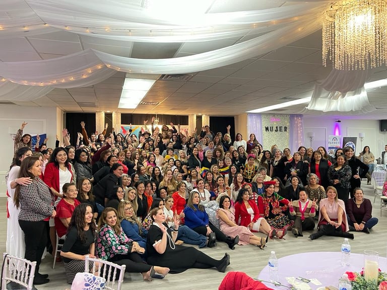 A large group of smiling professional women pose together at a Latina empowerment conference event.