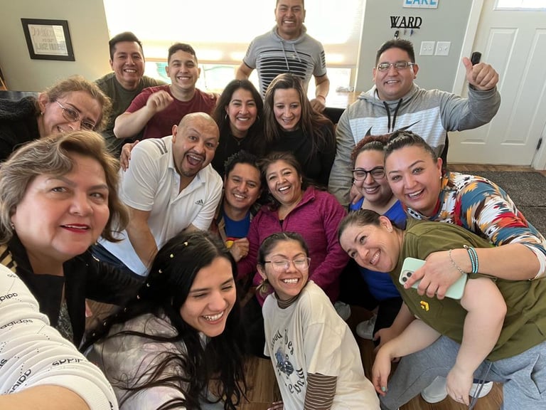 A large, diverse group of smiling family and friends gathering for a happy indoor photo celebration.