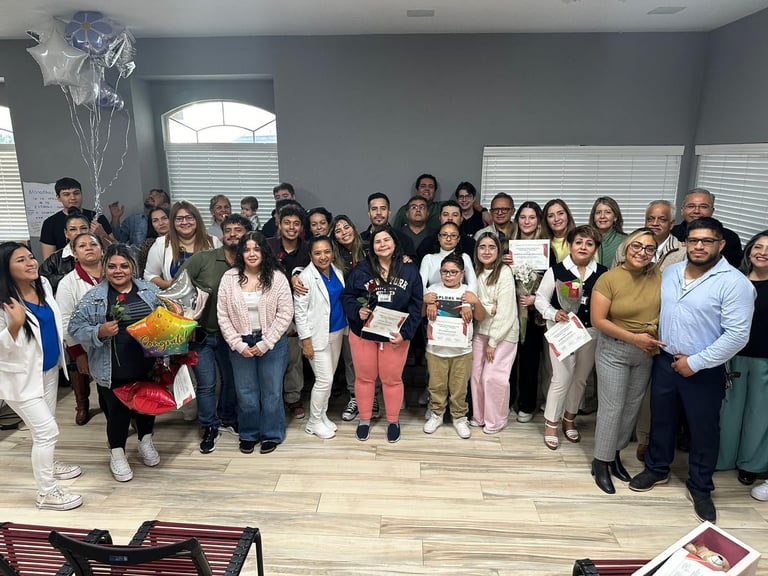 A diverse group of people posing for a graduation celebration photo holding certificates and balloons.