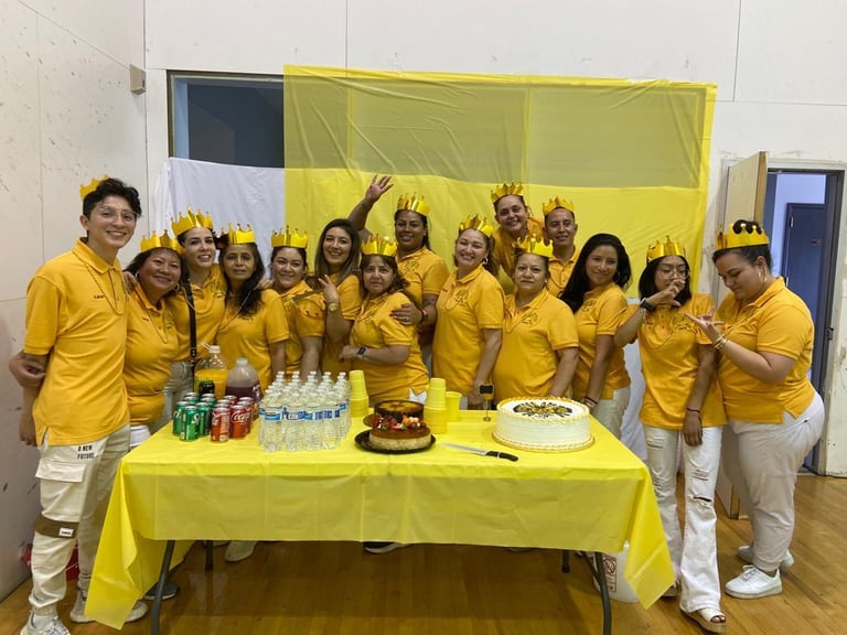 A group wearing yellow shirts and crowns celebrating at a party with cakes and drinks.