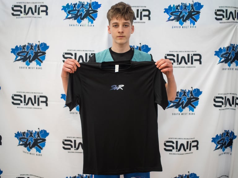 A boy holding a black SWR T-shirt
