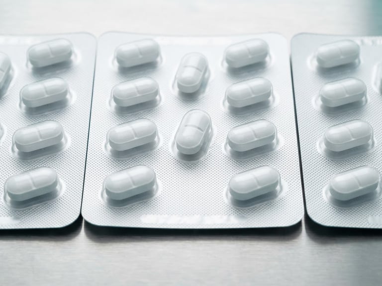 Macro shot of sealed pharmaceutical blister packs on a sterile steel surface, bright high-key clinical white light, sharp focus