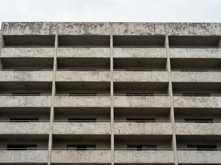 Close-up architectural detail of a well-finished Chennai apartment building facade — overcast daylight, straight-on human eye-level framing, concrete balconies and window reveals showing material quality, no people, no staging