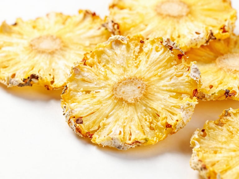 Macro shot of bright yellow dehydrated pineapple slices on a clean white surface, soft studio light, vibrant natural colors, macro depth of field