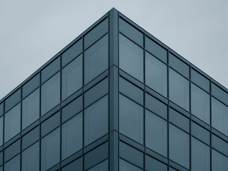 Minimalist architectural photography of a modern glass office building corner, clean geometric steel frame, overcast sky, desaturated blue and slate tones