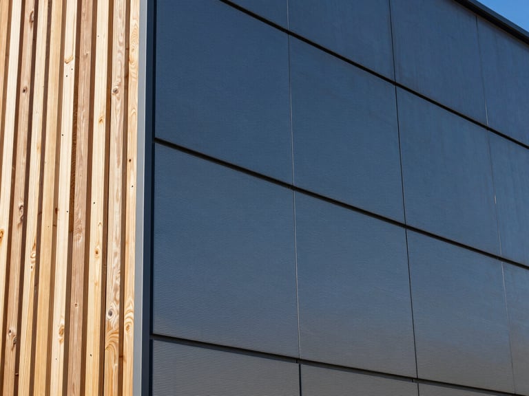 Close-up of a building's exterior showcasing a textured aluminum cladding panel next to a natural wooden slat, emphasizing clean lines and material quality.