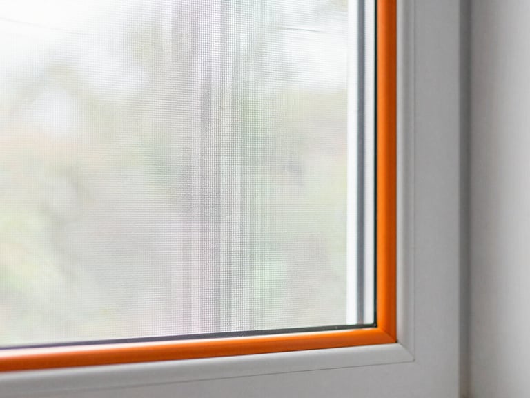Detail shot of a precisely installed window screen (kassa nyamuk), showing fine mesh and clean frame, natural daylight, 35mm