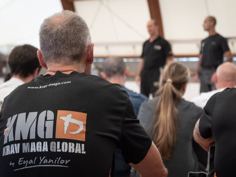 Students in Krav Maga Global t-shirts attend a self-defense seminar led by expert instructors.