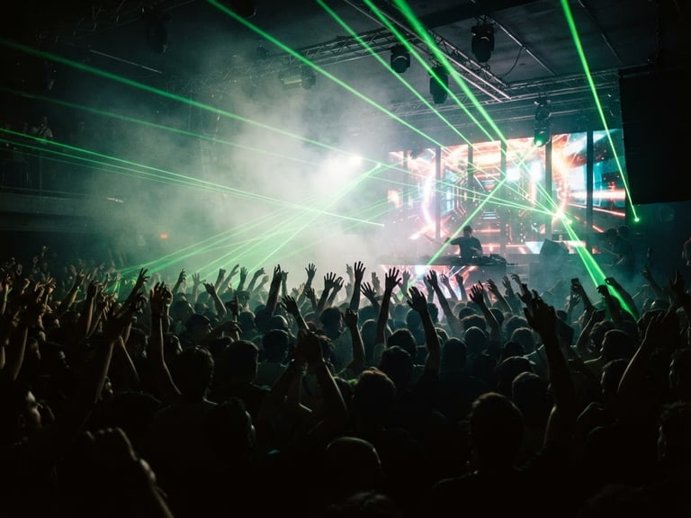 Dynamic concert photography, high-contrast green lasers piercing through thick smoke, a massive crowd with hands raised in front of a giant LED stage setup, Santiago club environment, 35mm film grain.