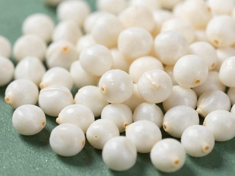 Macro shot of perfectly popped, snow-white makhana seeds on a clean dark green surface, bright natural daylight, extreme detail