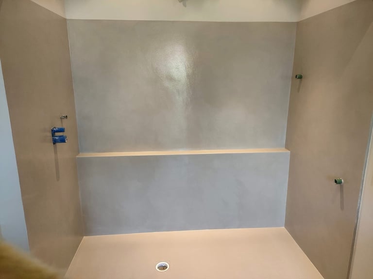 Modern walk-in shower with seamless waterproof microcement walls and a minimalist gray finish.