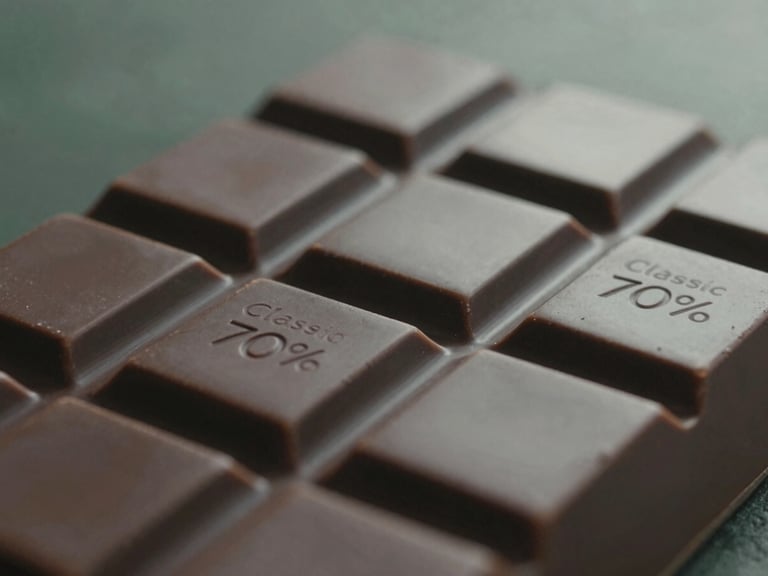 Close-up of a matte dark chocolate bar, Classic 70%, breaking cleanly, rich cacao-husk bronze tones, soft misty natural light, shallow depth of field