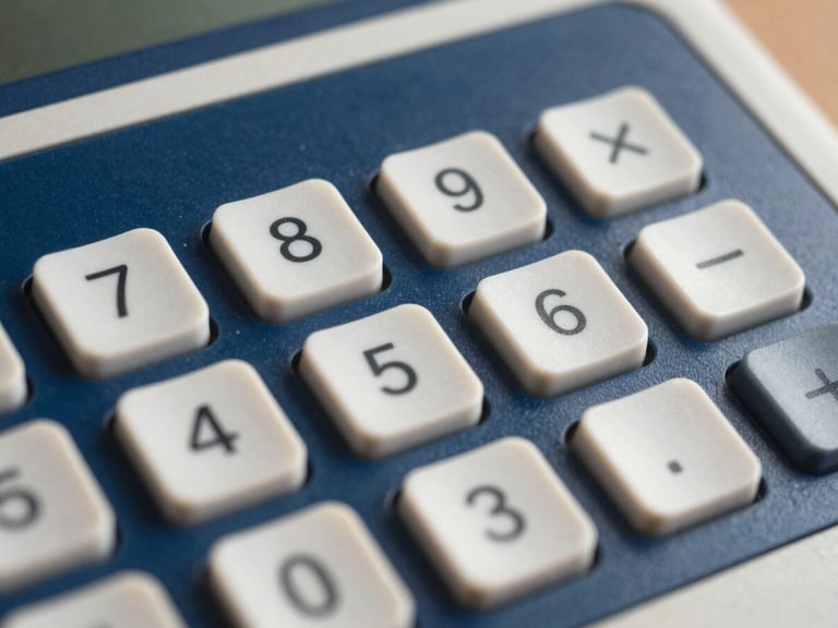 Close-up de uma calculadora ou tela de computador com gráficos financeiros simples e limpos, em tons de azul e branco, sem texto visível. Luz suave.