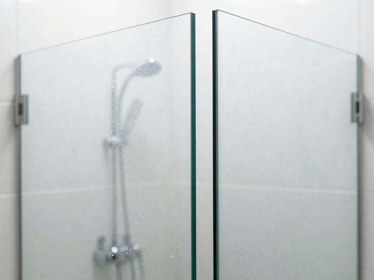 Crisp architectural macro shot of a frameless glass shower partition with flawless diamond-polished edges, clean water droplets sliding off, diffused natural daylight, 35mm