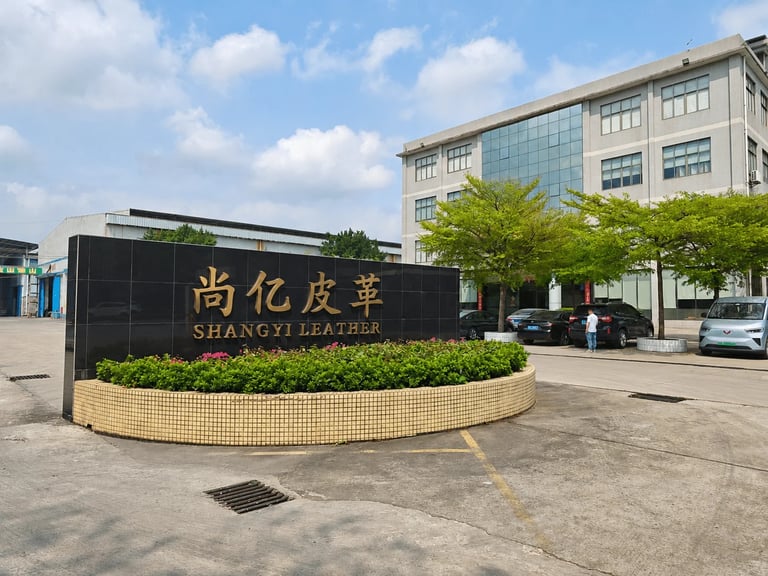 Shangyi Leather factory exterior with a black marble company sign and modern office building.