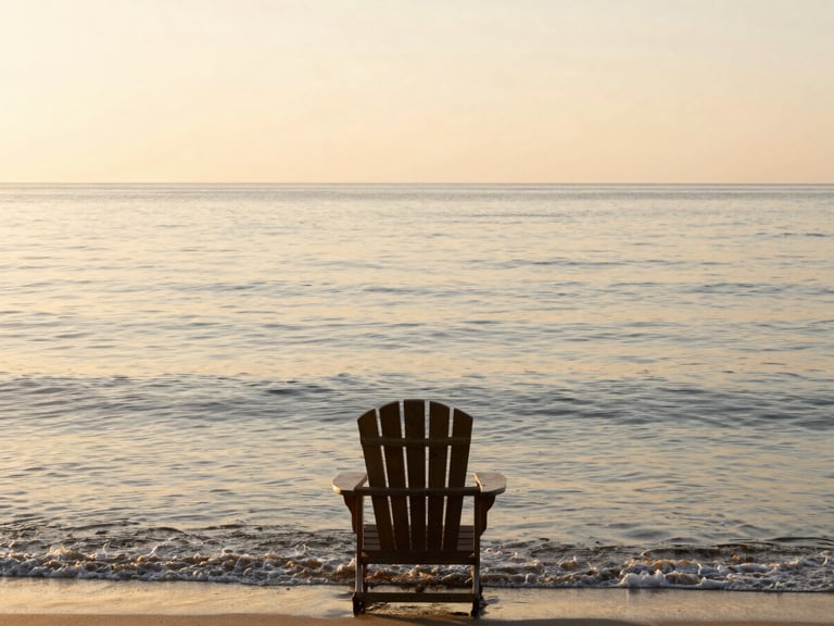 A wide panoramic view of a calm ocean at sunrise, gentle waves lapping the shore, a single, empty wooden Adirondack chair facing the water, soft amber light.