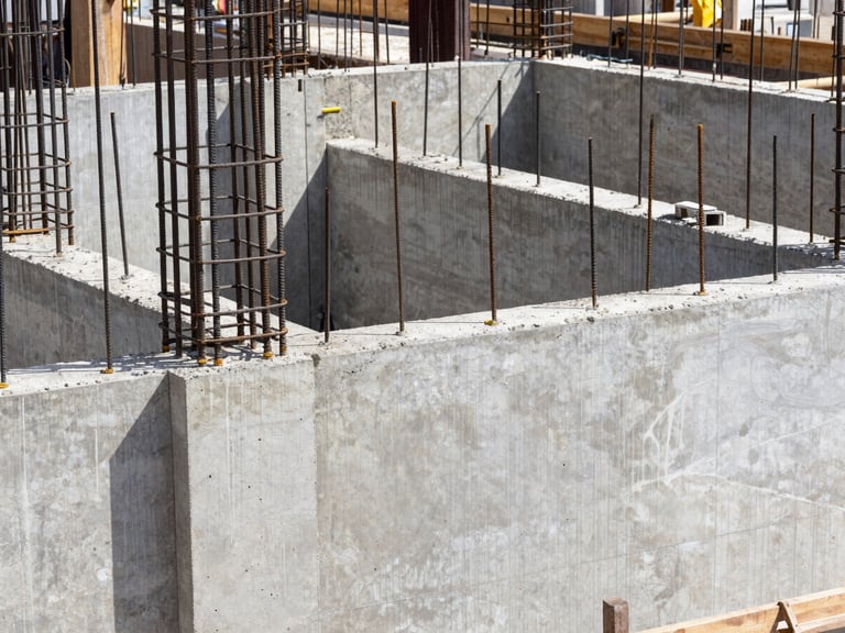 Close-up of high-contrast concrete formwork and steel reinforcement bars on an active Bali construction site under crisp daylight