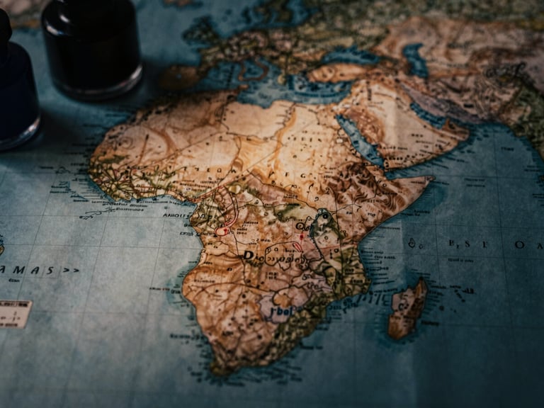 Macro close-up of a vintage map of East Africa, weathered paper, inkwells in soft focus, low-key dramatic lighting with deep shadows