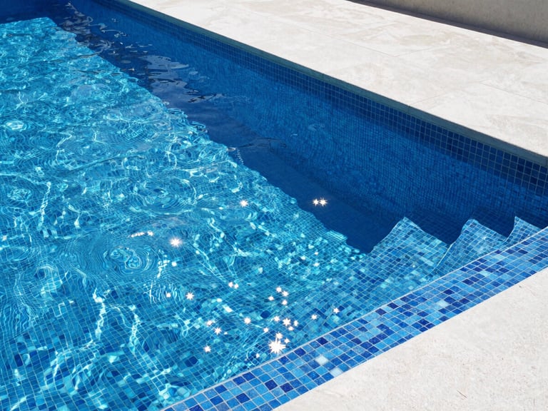 Detailed architectural shot of a swimming pool with premium blue mosaic tiles, sparkling clear water, crisp sunlight, modern concrete deck