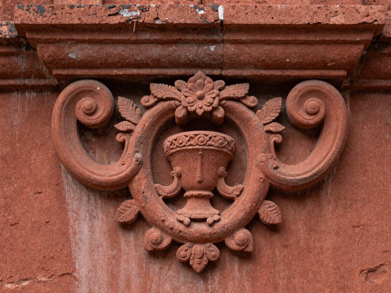 Detailed close-up of hand-carved baroque details on the red sandstone ruins of São Miguel, soft side lighting emphasizing texture.