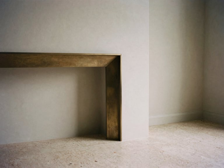 Detail shot of a minimalist living room corner, showing brushed bronze fireplace trim meeting seamless travertine flooring, soft afternoon directional light, medium format film.