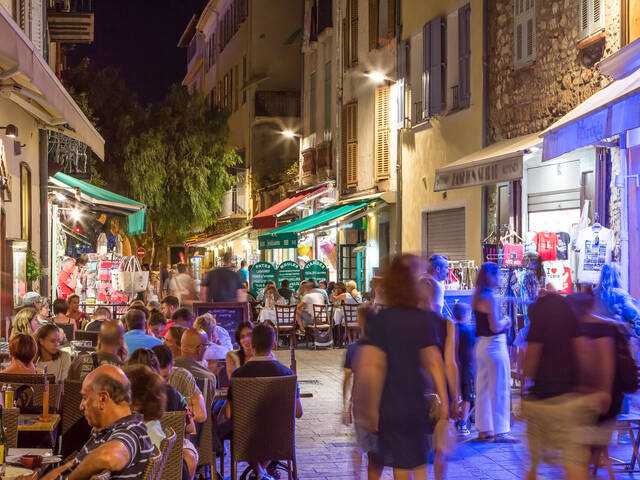 Juan les pins en soirée, des personnes assisent en terrasse de restaurant et d'autres marchent