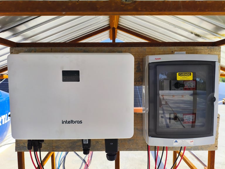 White Intelbras solar inverter and electrical string box mounted for a PV energy system.