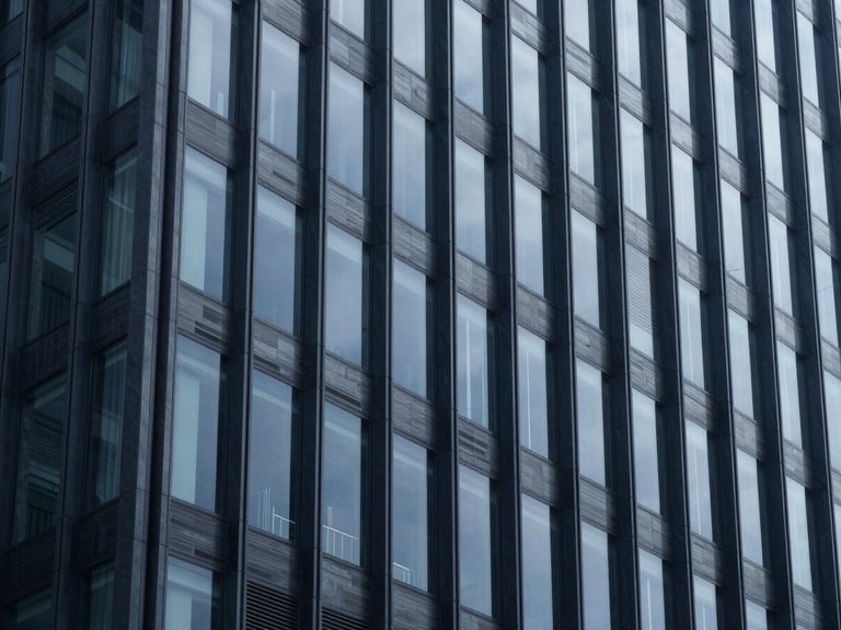 Modern corporate building facade, strong geometric lines, cool diffused office daylight, deep navy and slate tones.