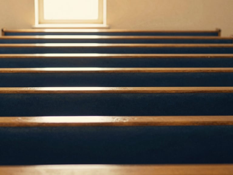 A warm, light-filled sanctuary with soft gold accents, empty wooden pews, light streaming through a window
