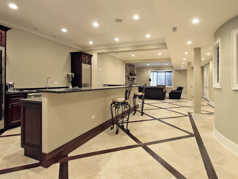 Modern finished basement featuring a wet bar with dark wood cabinets and unique diamond pattern tile flooring.