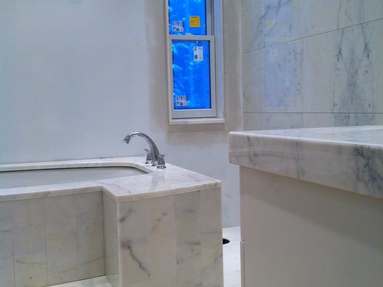 Modern luxury bathroom under construction with white marble tile bathtub and matching vanity.