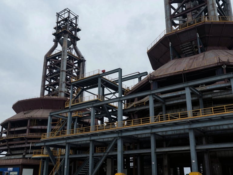 Wide environmental shot of architectural geometry in heavy industry, structural steel framework, overcast daylight, cool low-key lighting.