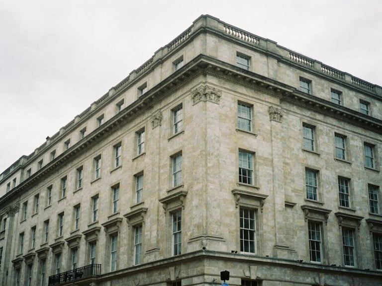 Wide architectural angle of a classic Portland stone facade on Oxford Street, overcast London sky, soft low-contrast diffused daylight, moody editorial photography, 35mm film grain.